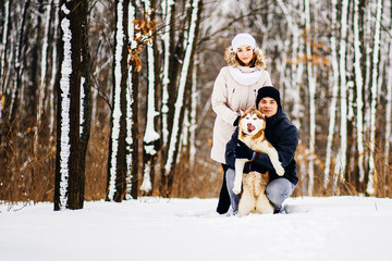 Fototapeta premium A young couple walking in the forest with the dog red husky. Toned