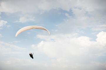 Alone paraglider flying in the blue sky against the background of clouds. Paragliding in the sky on...