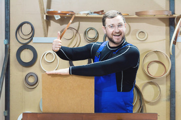 The manufacturer of furniture in special clothes and glasses holds an empty plate for text while in...