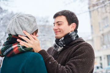 Young loving couple dressed in plaid scarves walk at the old city in winter