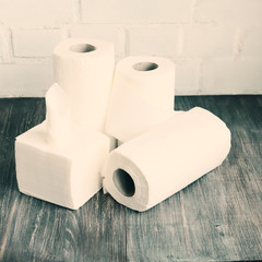 White kitchen paper towel, toilet paper, tissue, napkins on a dark wooden table. Concept of kitchen and hygienic disposables.