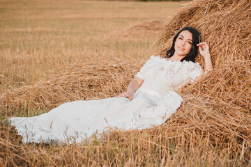 Beautiful young woman on the dried haystack