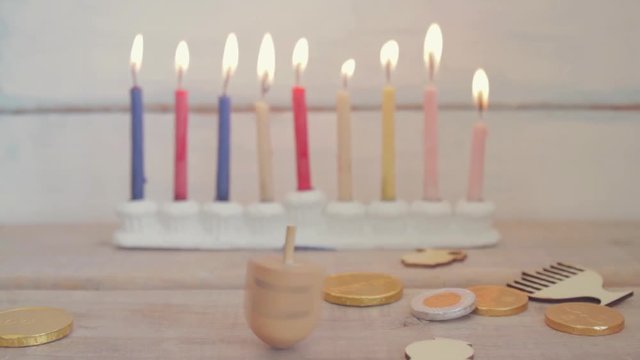 Hanukkah dreidel spinning with menorah light and Hanukkah coins on a vintage wood background