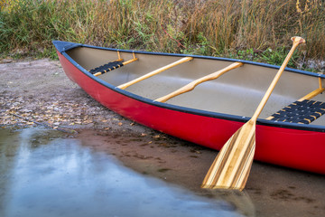 red canoe on a lake shore