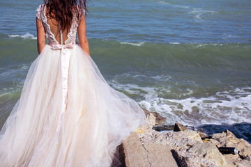 Fototapeta na wymiar Woman in wedding dress looking at the ocean