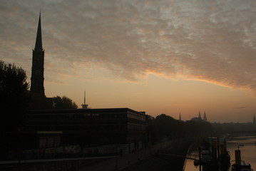 Sunrise in Bremen city in summer with trees on river weser and beautifyl sky clouds