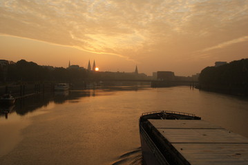 Fototapeta premium Sunrise in Bremen City view on Weser river with a transport vessel boat going on weser