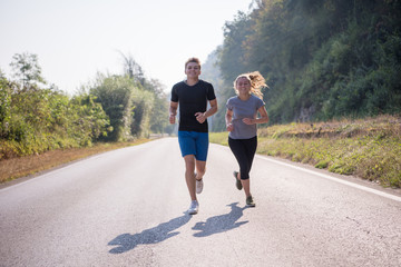 young couple jogging along a country road