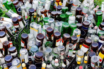 Empty glass bottles in plastic boxes on the grass.