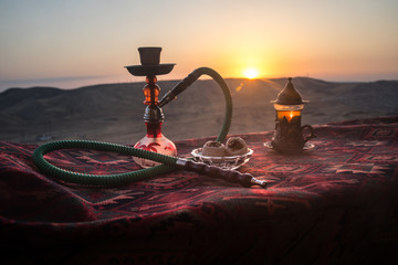 Hookah hot coals on shisha bowl making clouds of steam at desert outdoor. Oriental ornament on the...