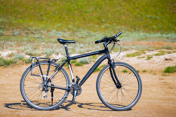 Fototapeta na wymiar closeup black touristic bicycle among a prairie