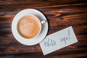 Wake up text near cup of coffee. Font of lettering word on white paper by calligrapher. Morning, handwriting, lettering, concept.