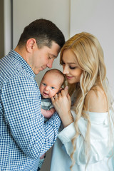 beautiful young family holding their baby in their arms at home