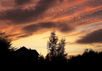Sunset or sunrise, dramatic sky over the roof of the house, colorful background. Selective focus.