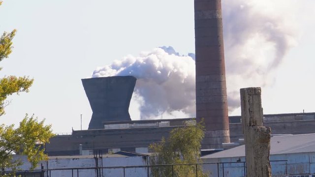 Smoke from the Chimneys of Industrial Metallurgical Plant Rises in the Atmosphere near the City. Throws toxic substances into the sky. Heavy smoke, vapor and exhaust gases. Smoke rises into the clouds