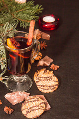 mulled wine with fragrant spices on a dark leather background with chocolate chip cookies a branch of a Christmas tree and New Year's decor