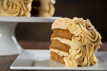 Close up of a slice of pumpkin spice cake with cake and flowers in the background