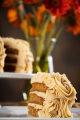 Decadent slice of pumpkin spice cake with cake and flowers in the background