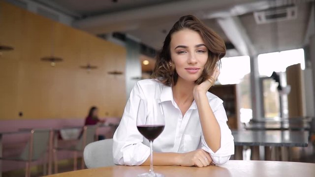 Pretty woman portrait with wine in a restaurant leaning head to hand
