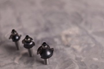 Row of three steel router bits for milling cutter on old broken worn gray concrete floor with copy...