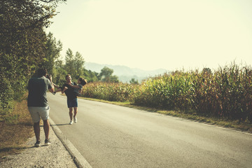 Obraz premium videographer recording while couple jogging along a country road