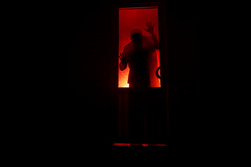 Silhouette of an unknown shadow figure on a door through a closed glass door. The silhouette of a human in front of a window at night. Scary scene halloween concept