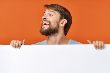 joyful man with a white paper on red background free space