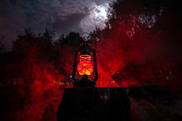 Horror Halloween concept. Burning old oil lamp in forest at night. Night scenery of a nightmare...