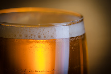 Amber beer on a Golden background. Foam hop drink. Place for your text.