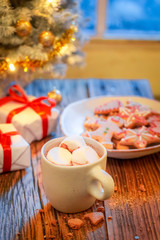 Hot chocolate, sweet gingerbread cookies and Christmas tree with gifts