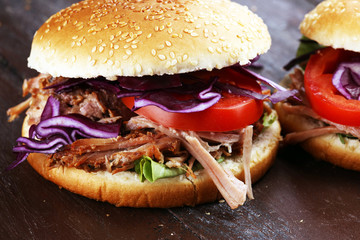 Pulled pork sandwiches with BBQ sauce, cabbage and tomato on table