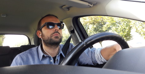 Uomo alla guida dell'auto - telefonata con auricolari 