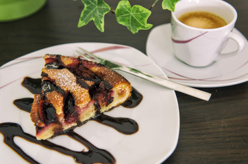 A hot coffee with a piece of plum cake