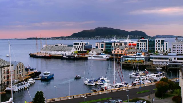 Alesund, Norway. A timelapse of the bay at sunset in Alesund, Norway, on a cloudy evening with numerous yachts, boats and a ferry docking at the waterfront.