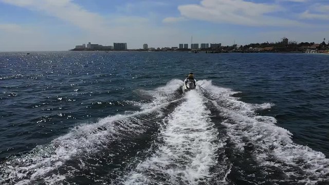Slow motion high definition footage of jet ski rider in blue water, taken off shores in Cancun Mexico using drone