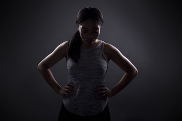 Silhouette of black female in an angry pose or portrait of an athlete concentrating for an extreme sport competition. The face is in shadow to portray anger or rage.
