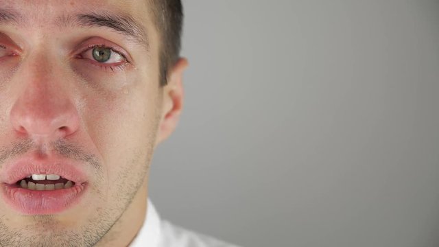 Half face portrait of depressed man crying with tears in eye. Man in despair.