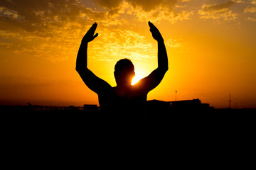 Silhouette of man with their hands in the sunset. Outdoor shot