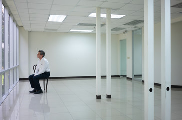 Businessman seating  in empty bright office and look outside thinking