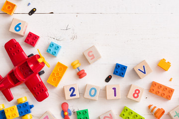 Closeup of children multi-color plastic bricks with figures 2018 on white wooden background. Early...