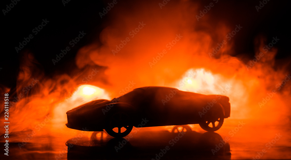 Wall mural the car in the shadows with glowing lights in low light, or silhouette of sport car dark background.