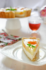 A slice of cheesecake with peaches and jelly on a table at teatime