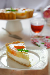 A slice of cheesecake with peaches and jelly on a table at teatime