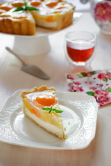A slice of cheesecake with peaches and jelly on a table at teatime