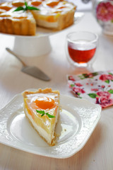A slice of cheesecake with peaches and jelly on a table at teatime