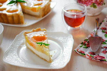 A slice of cheesecake with peaches and jelly on a table at teatime