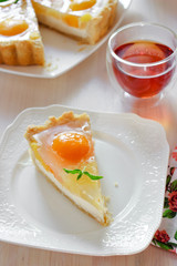 A slice of cheesecake with peaches and jelly on a table at teatime
