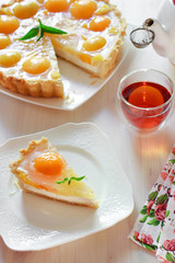 A slice of cheesecake with peaches and jelly on a table at teatime