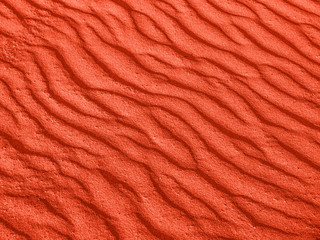 texture of red sand waves on the beach or in the desert. the ripples of the sand is diagonal.