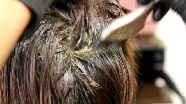 Series of closeup of hair dresser applying chemical color dye onto hair of customer in salon 


